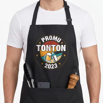 Tablier de cuisine noir avec motif Promu Tonton 2023 illustrant une bière et un biberon dans un cercle coloré.