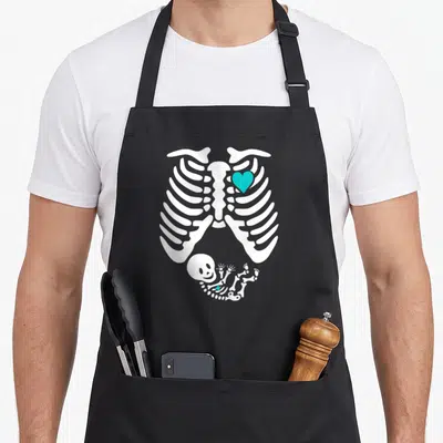 Tablier de cuisine noir avec illustration squelette de grossesse X-ray et bébé sourire turquoise.
