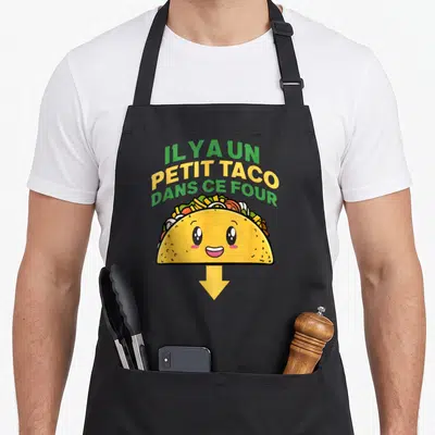 Tablier de cuisine noir avec un taco souriant et le texte Il y a un petit taco dans ce four au centre.