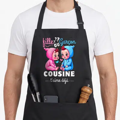 Tablier de cuisine noir avec illustration de deux bébés rose et bleu et le texte cousine t'aime déjà.