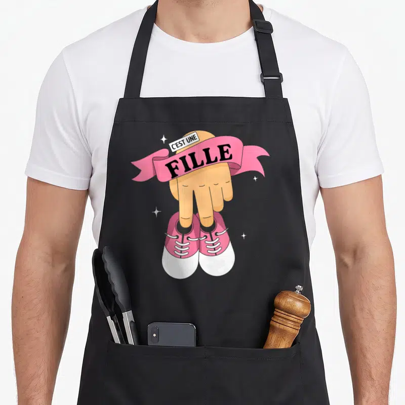 Tablier de cuisine noir avec une main pointant vers des chaussettes roses et le texte C'est une Fille.