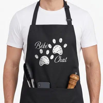 Tablier de cuisine noir avec inscription Bébé Chat et deux traces de pattes blanches stylisées au centre.