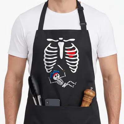 Tablier de cuisine noir avec illustration squelette pirate et cage thoracique contenant un cœur rouge.