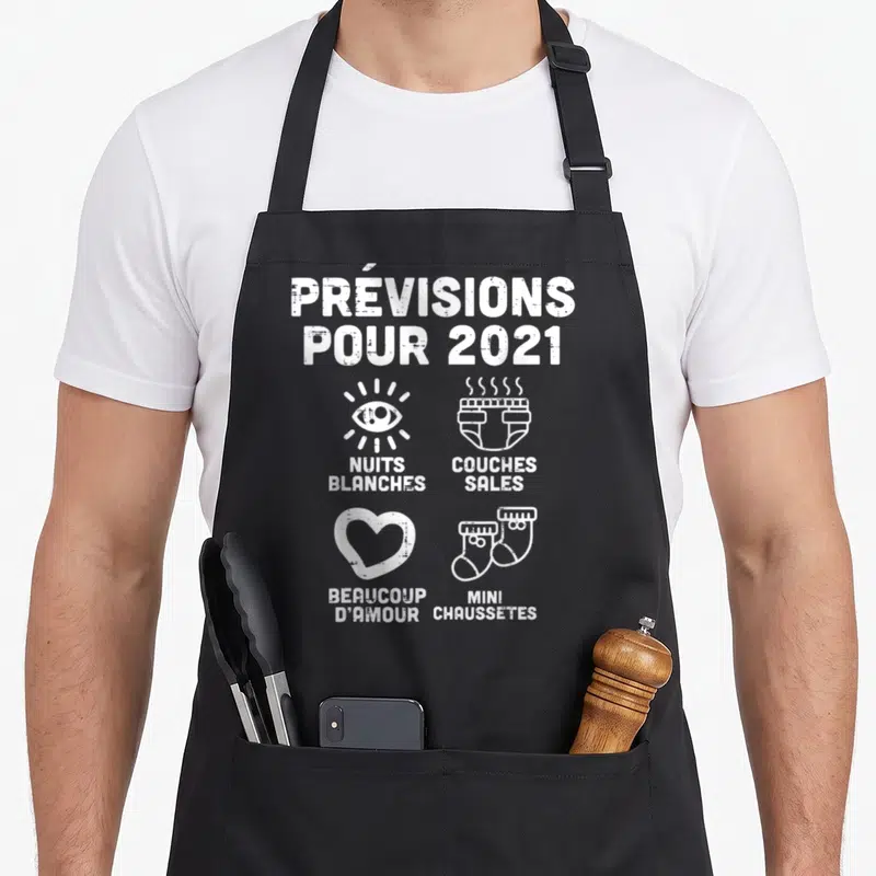 Tablier de cuisine noir avec le texte Prévisions Pour 2021 et des icônes nuits blanches, couches sales, amour et mini chaussettes en blanc.