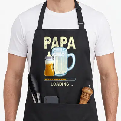 Tablier de cuisine noir avec illustration d'un biberon rempli de bière à côté d'une grande mug et du texte Papa Loading.