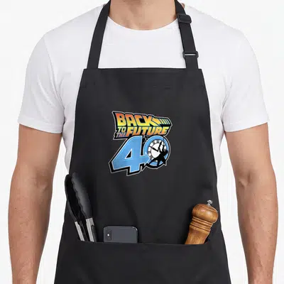 Tablier de cuisine noir avec le logo Back to the Future 40ème anniversaire en couleurs vives sur fond uni.