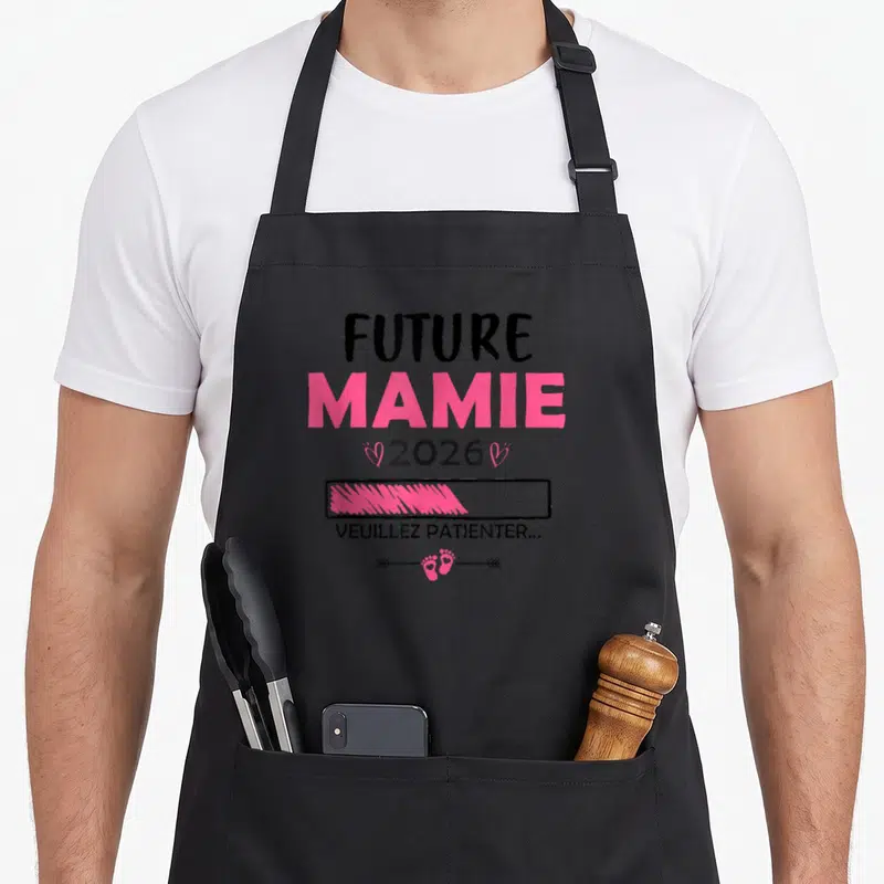Tablier de cuisine noir avec texte Future Mamie 2026 et icône de petites pattes roses