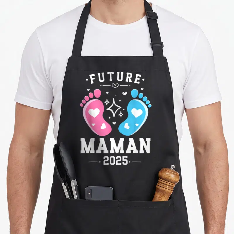 Tablier de cuisine noir avec l'inscription Future Maman 2025 et deux petits pieds colorés ornés de cœurs blancs.