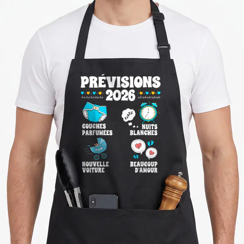 Tablier de cuisine noir avec illustration colorée annonçant des couches parfumées et une nouvelle voiture pour l'année 2026.