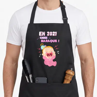 Tablier de cuisine noir avec illustration d'un bébé en pyjama rose criant et le texte En 2021 j'casse la baraque.