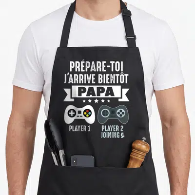 Tablier de cuisine noir avec l'inscription Prépare-toi j'arrive bientôt Papa et deux manettes de jeu vidéo Player 1 et Player 2 Joining.