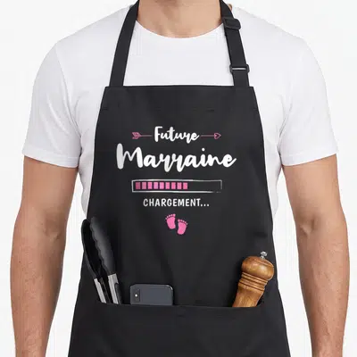 Tablier de cuisine noir avec inscription Future Marraine Chargement et empreintes de pieds roses.