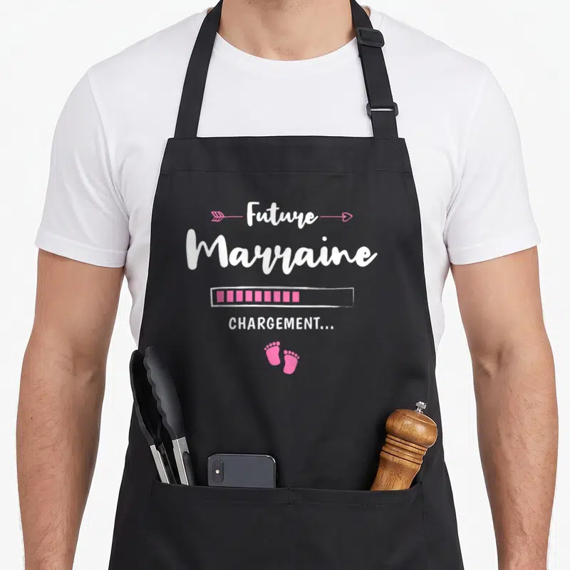 Tablier de cuisine noir avec inscription Future Marraine Chargement et empreintes de pieds roses.