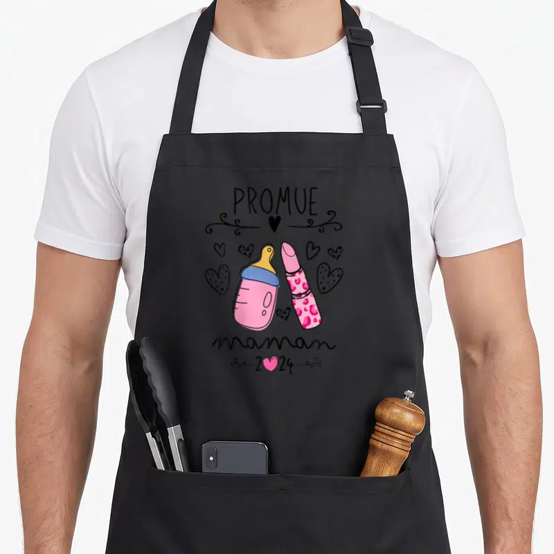 Tablier de cuisine noir avec illustration d'un biberon, d'un rouge à lèvres et du texte Promue maman 2024.