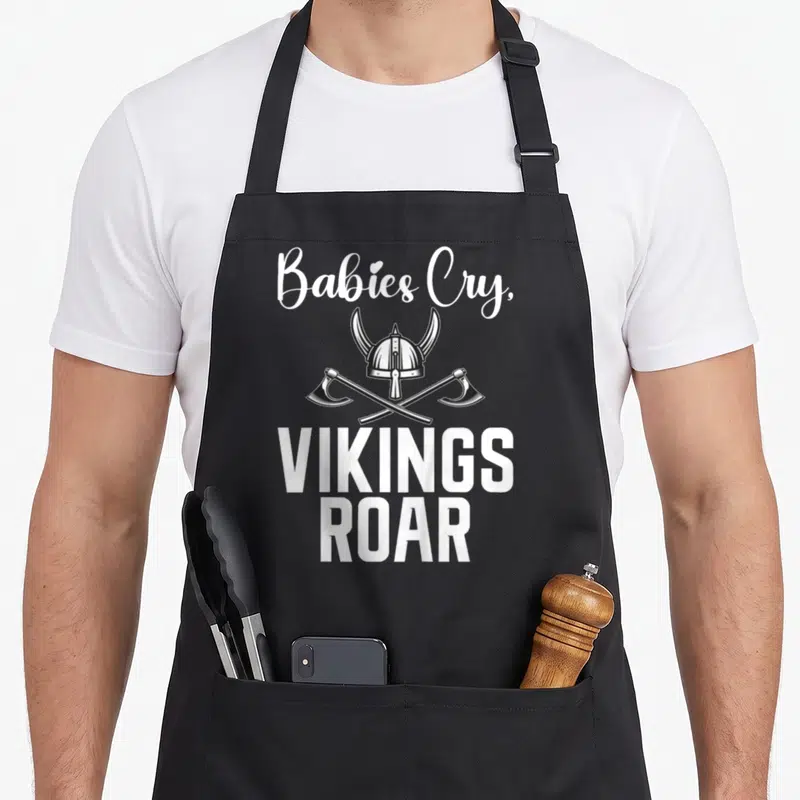 Tablier de cuisine noir avec inscription « Babies Cry, VIKINGS ROAR » et casque viking croisé d'axes.