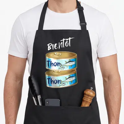 Tablier de cuisine noir avec deux canettes de thon et le texte Bientôt Tonton imprimé en blanc.