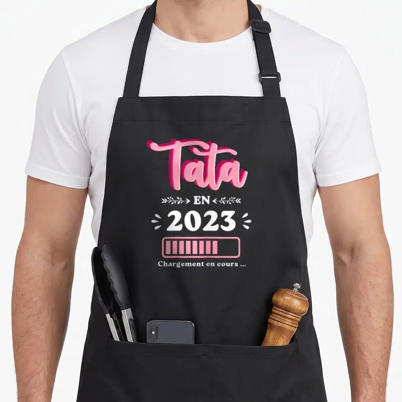 Tablier de cuisine noir avec inscription Tata 2023 et barre de chargement rose et blanche.