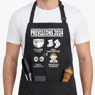 Tablier de cuisine noir avec illustration Prévisions 2024 montrant des chaussettes et un bébé souriant.