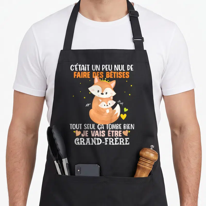 Tablier de cuisine noir avec un renard orange portant une couronne et un petit renard, entouré d'étoiles et de cœurs.