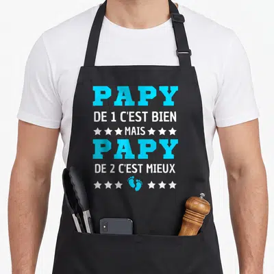 Tablier de cuisine noir avec inscription Papy de 2 c'est mieux et empreintes de pieds bleues.