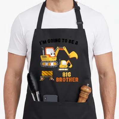 Tablier de cuisine noir avec deux pelles jaunes souriantes et le texte I'm going to be a Big Brother.