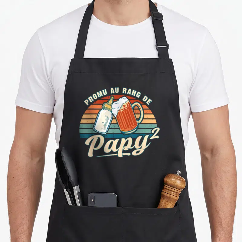 Tablier de cuisine noir avec motif Promu au rang de Papy 2 illustré par un biberon et une bière.