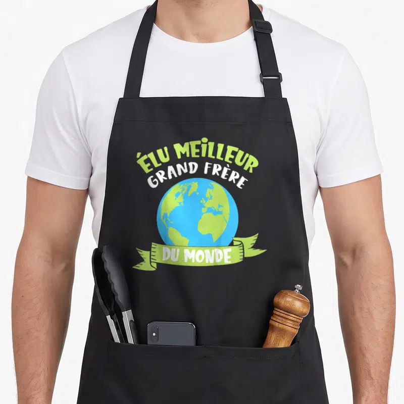 Tablier de cuisine noir avec une illustration de la planète et le texte Élu Meilleur Grand Frère du Monde en vert et blanc.