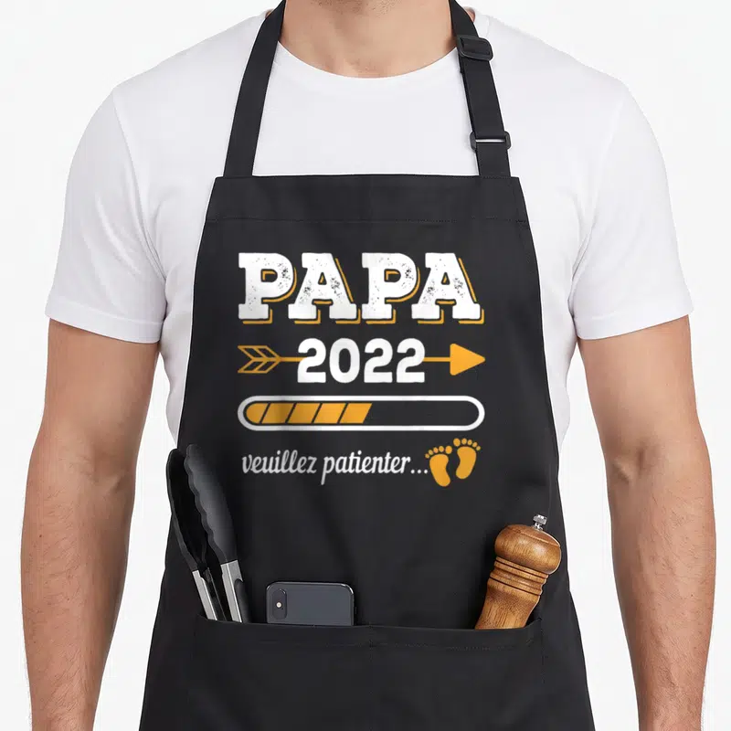 Tablier de cuisine noir avec inscription Papa 2022 et barres de progression orange illustrant l'attente d'un bébé.