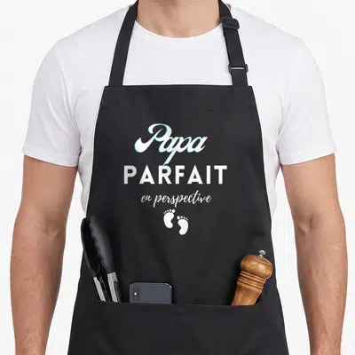 Tablier de cuisine noir avec l'inscription Papa parfait en perspective et deux petits pieds blancs.