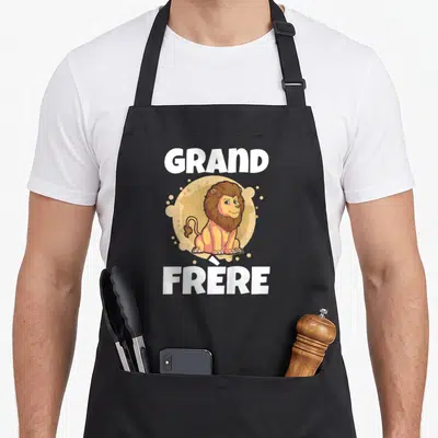 Tablier de cuisine noir avec illustration d'un lion et texte Grand Frère en blanc.