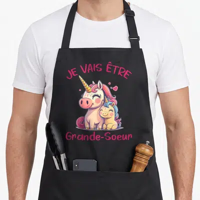 Tablier de cuisine noir avec deux licornes mignonnes et le texte Je vais être Grande-Soeur en lettres roses.