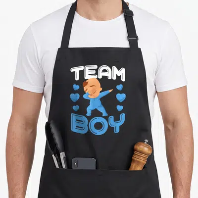 Tablier de cuisine noir avec illustration d'un bébé en bleu effectuant un dab sous le texte Team Boy.