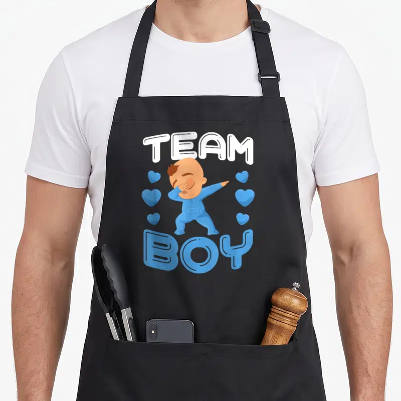 Tablier de cuisine noir avec illustration d'un bébé en bleu effectuant un dab sous le texte Team Boy.