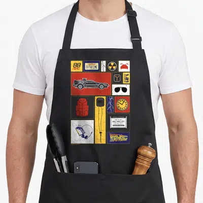 Tablier de cuisine noir avec collage d'icônes « Retour vers le futur » incluant DeLorean, Outatime et Hill Valley.