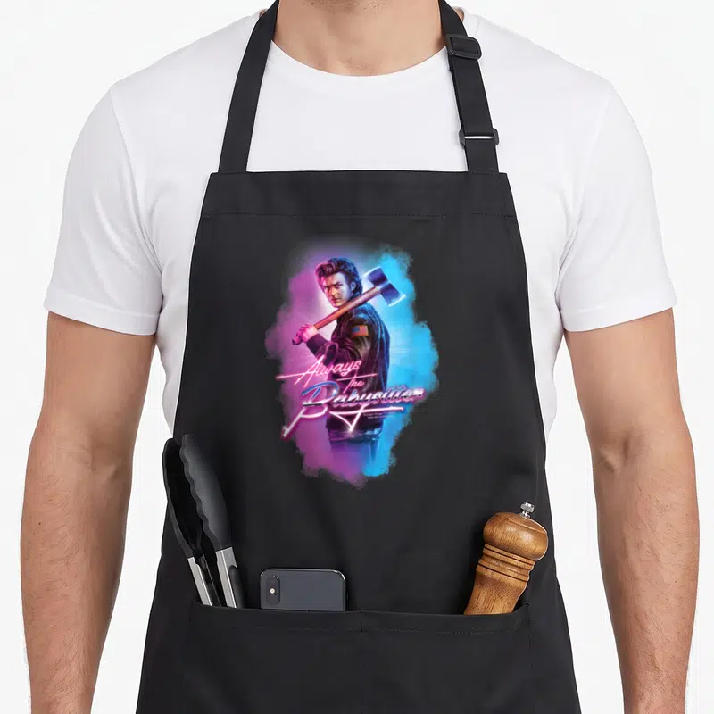 Tablier de cuisine noir avec illustration de Steve Harrington tenant une hache sous un effet lumineux néon rose et bleu.