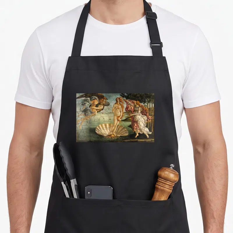 Tablier de cuisine noir avec une reproduction de La naissance de Vénus imprimée sur le devant.