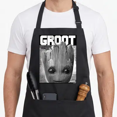 Tablier de cuisine noir avec un portrait en gros plan de bébé Groot et le texte GROOT en lettres capitales blanches sur fond sombre.