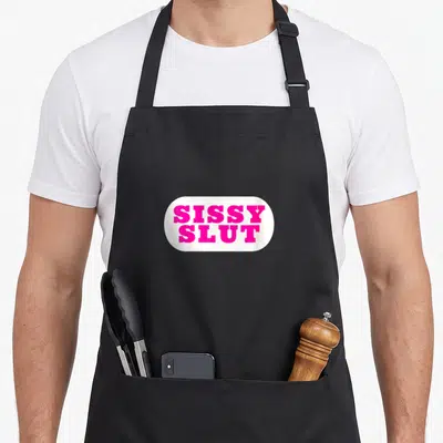 Tablier de cuisine noir avec un motif rectangulaire blanc portant les mots Sissy Slut en lettres roses vives.