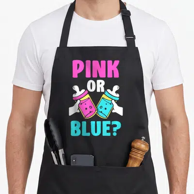 Tablier de cuisine noir avec deux biberons rose et bleu et le texte Pink or Blue en lettres colorées.