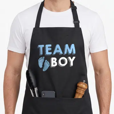 Tablier de cuisine noir avec texte Team Boy et illustration de petits pieds bleus de bébé.