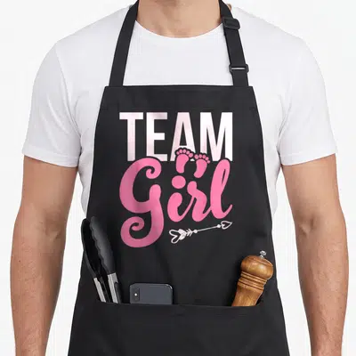Tablier de cuisine noir avec texte Team Girl rose, petits pieds et flèche cœur.
