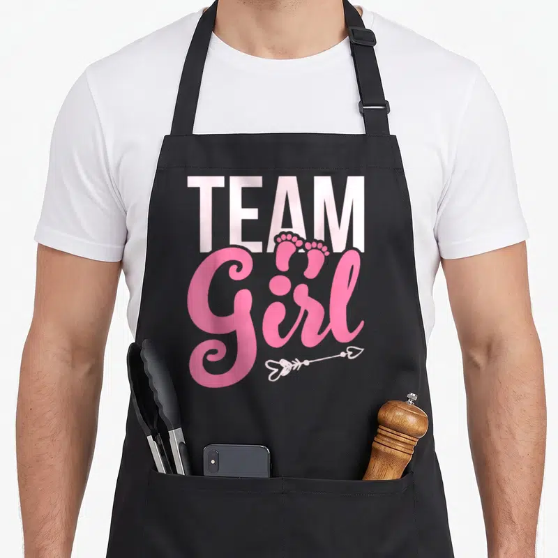 Tablier de cuisine noir avec texte Team Girl rose, petits pieds et flèche cœur.