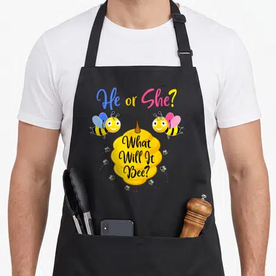 Tablier de cuisine noir avec deux abeilles colorées et une ruche jaune imprimée au centre.