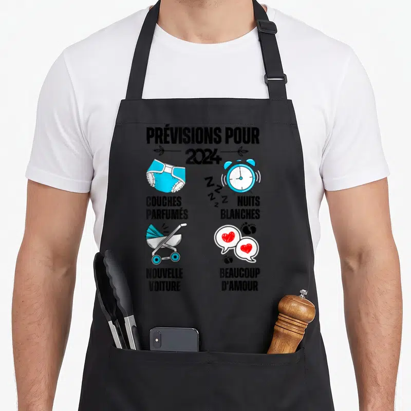 Tablier de cuisine noir avec illustration humoristique sur la grossesse et l'arrivée d'un bébé en 2024.