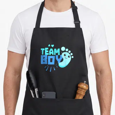 Tablier de cuisine noir avec l'inscription Team Boy et un petit pied bleu mignon aux yeux ronds.