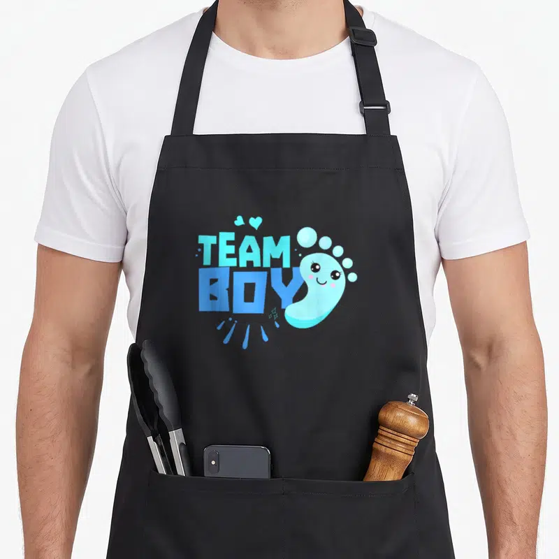 Tablier de cuisine noir avec l'inscription Team Boy et un petit pied bleu mignon aux yeux ronds.