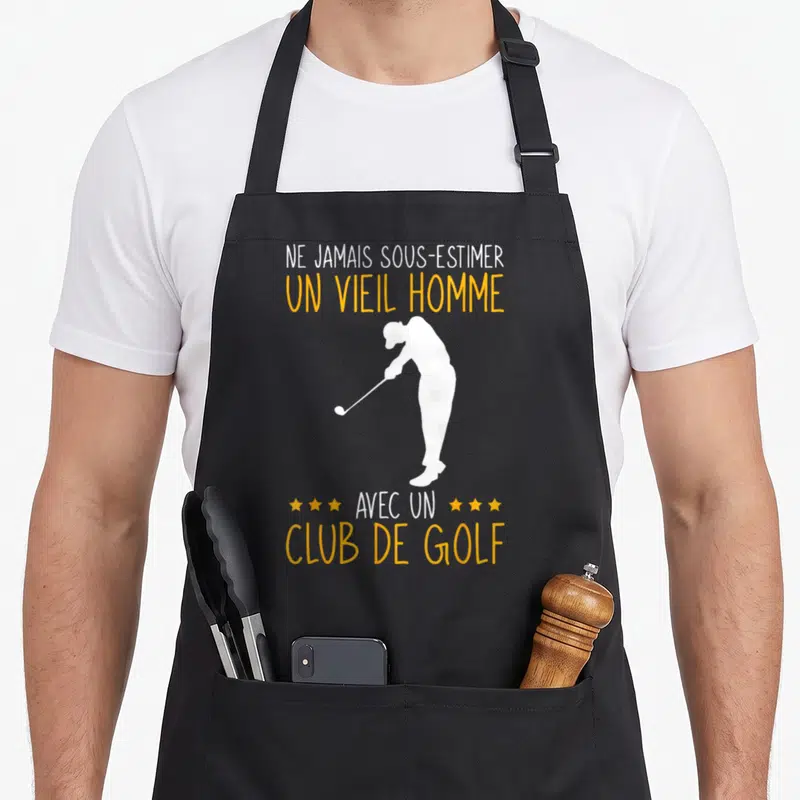 Tablier de cuisine noir avec silhouette blanche de golfeur et texte jaune Ne jamais sous-estimer un vieil homme avec un club de golf.