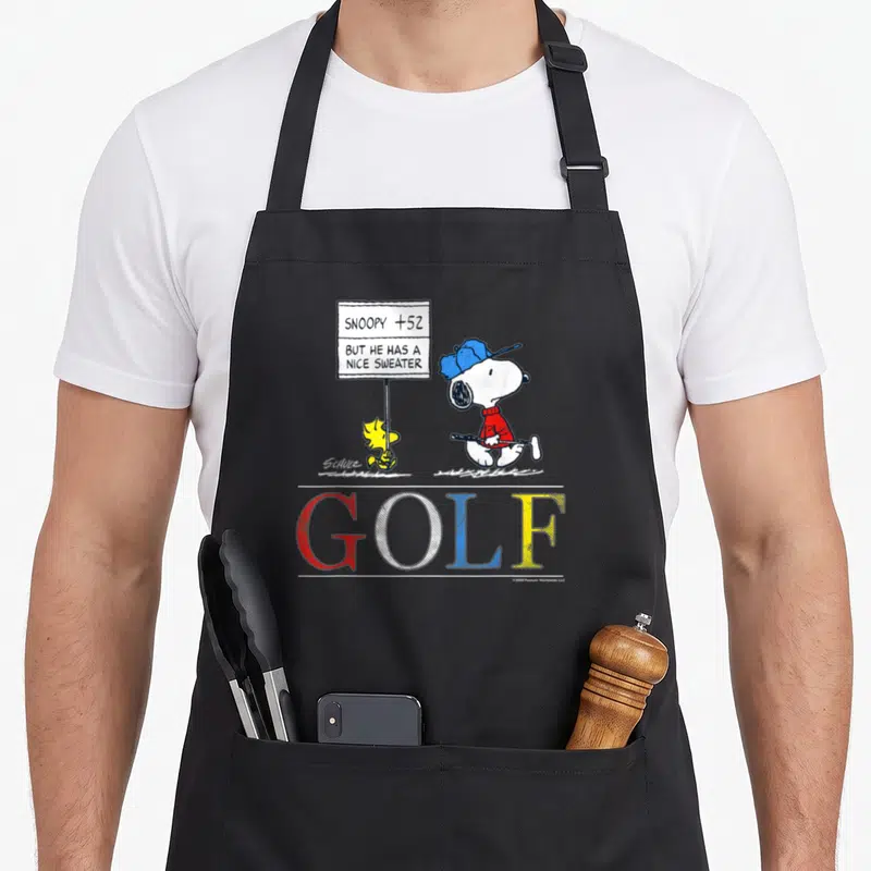 Tablier de cuisine noir avec Snoopy en golfeur, Woodstock et une pancarte de score humoristique.