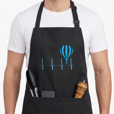 Tablier de cuisine noir avec illustration bleue d'une montgolfière sur une ligne de rythme cardiaque.