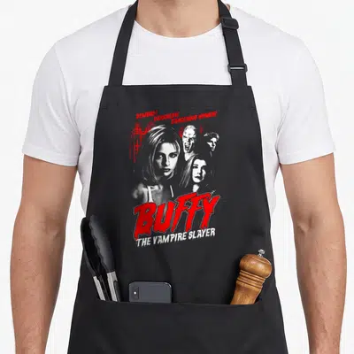 Tablier de cuisine noir avec motif rouge et blanc représentant Buffy et des démons dans un style affiche d'horreur vintage.